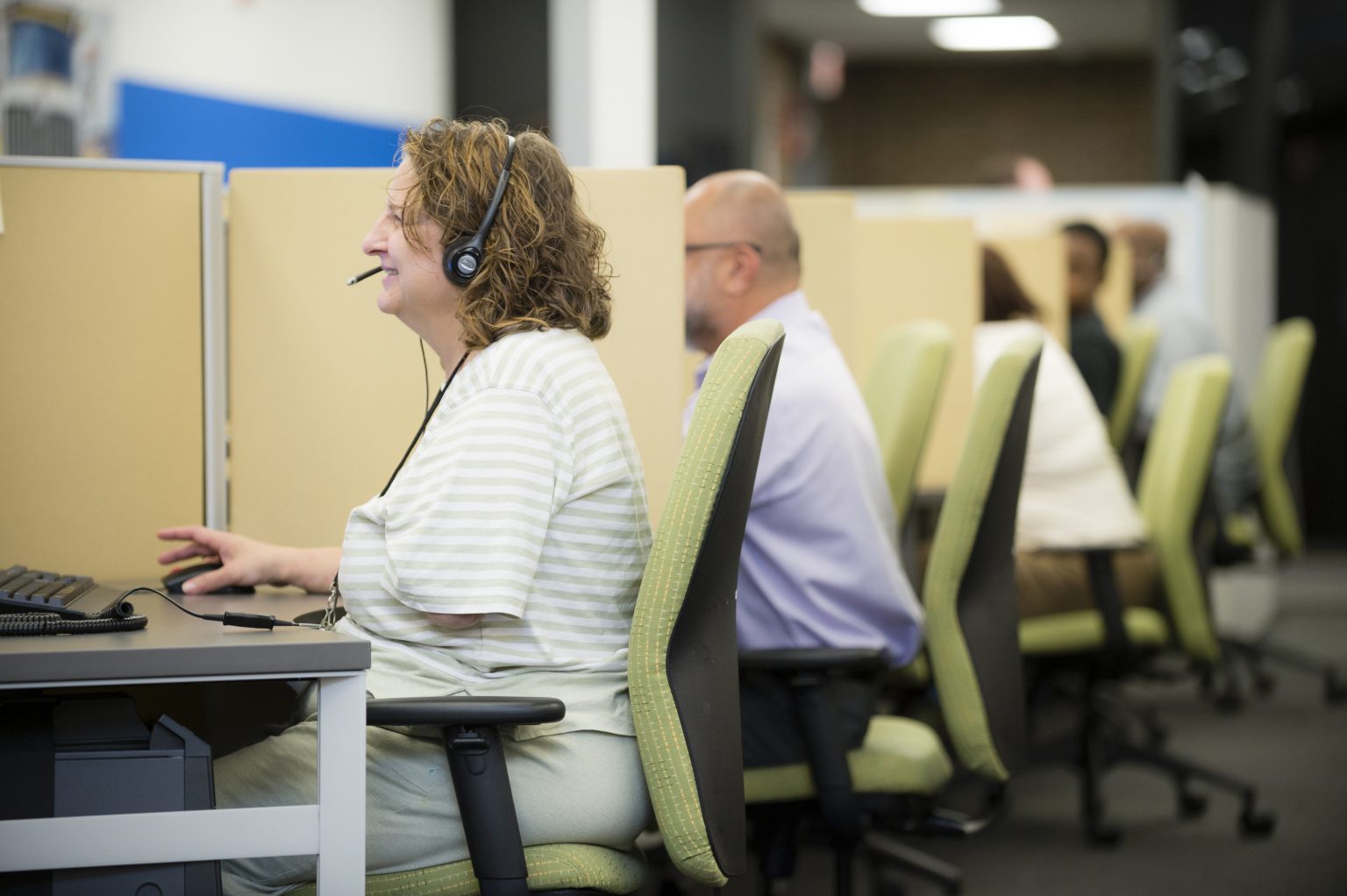 Lighthouse Enterprises agent in a headset working at her computer on the contact center floor