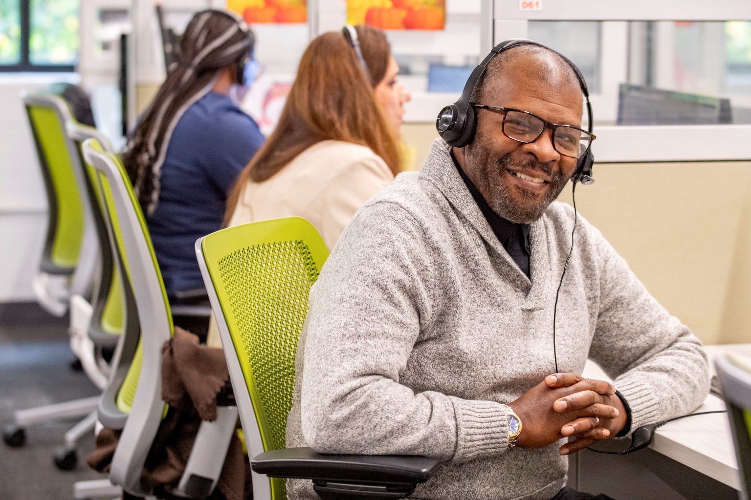 Lighthouse Enterprises agent in a headset smiling at his workstation on the UI Health program floor